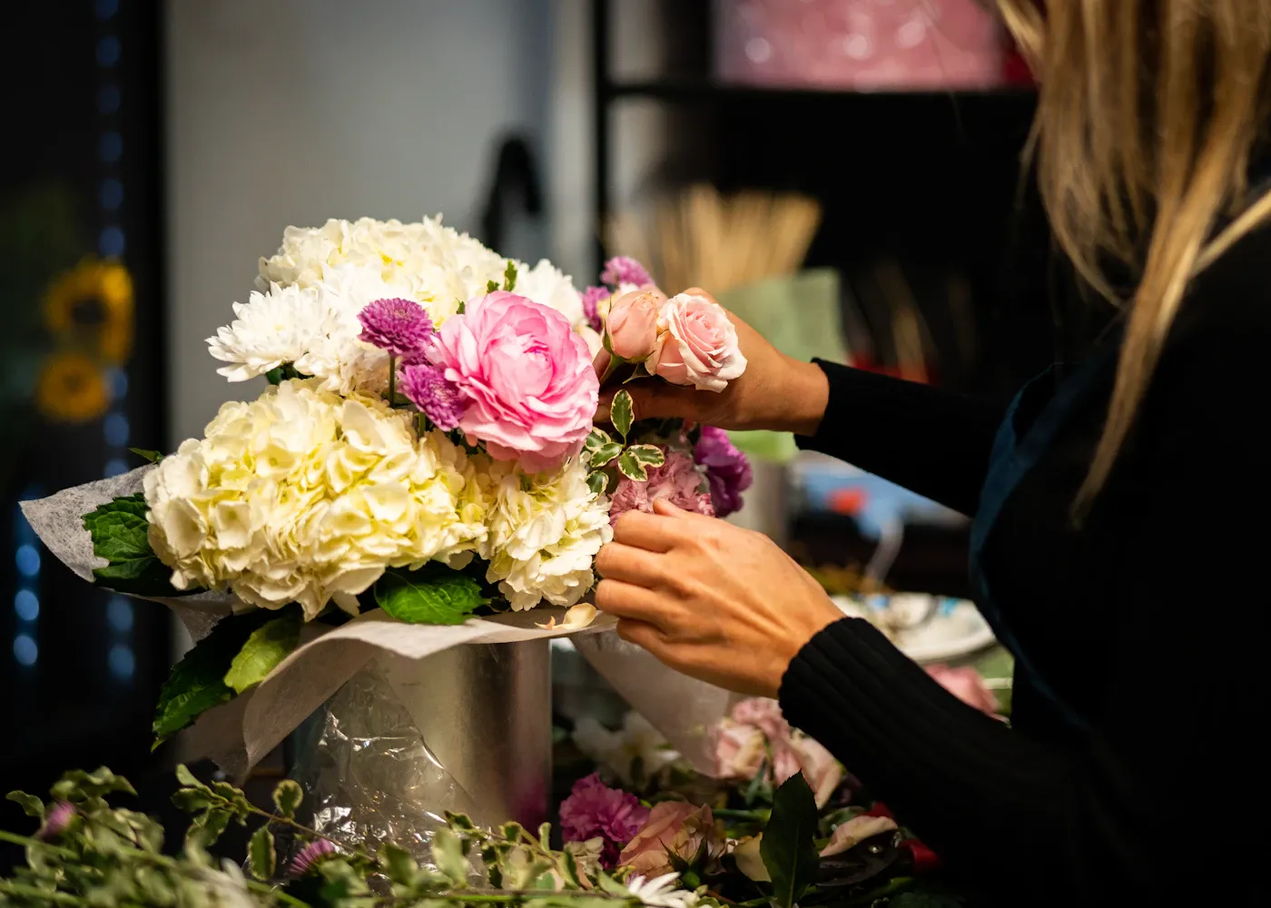 Hands arranging a bouquet of peonies and hydrangeas