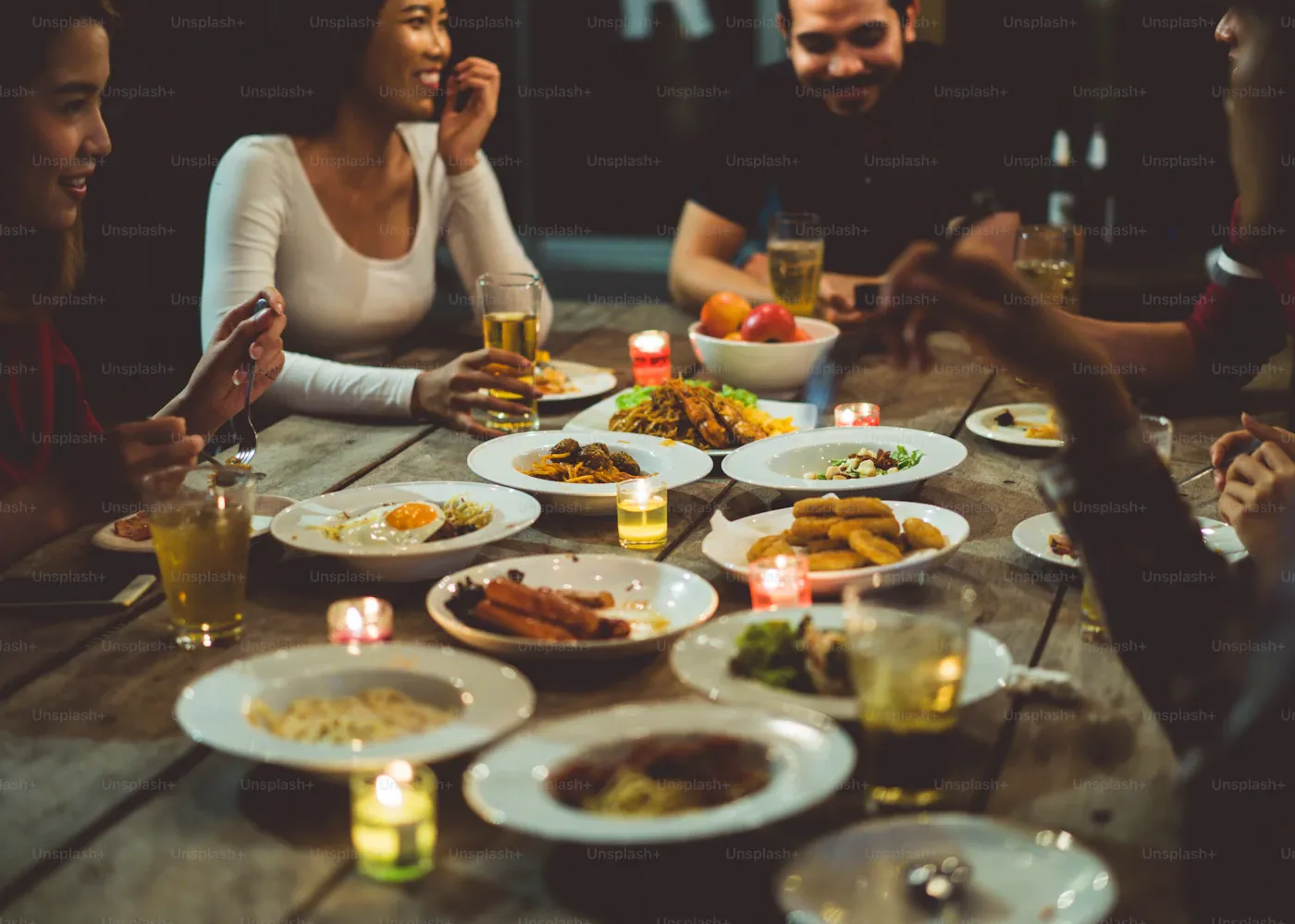 Friends sharing a candlelit dinner at a long table