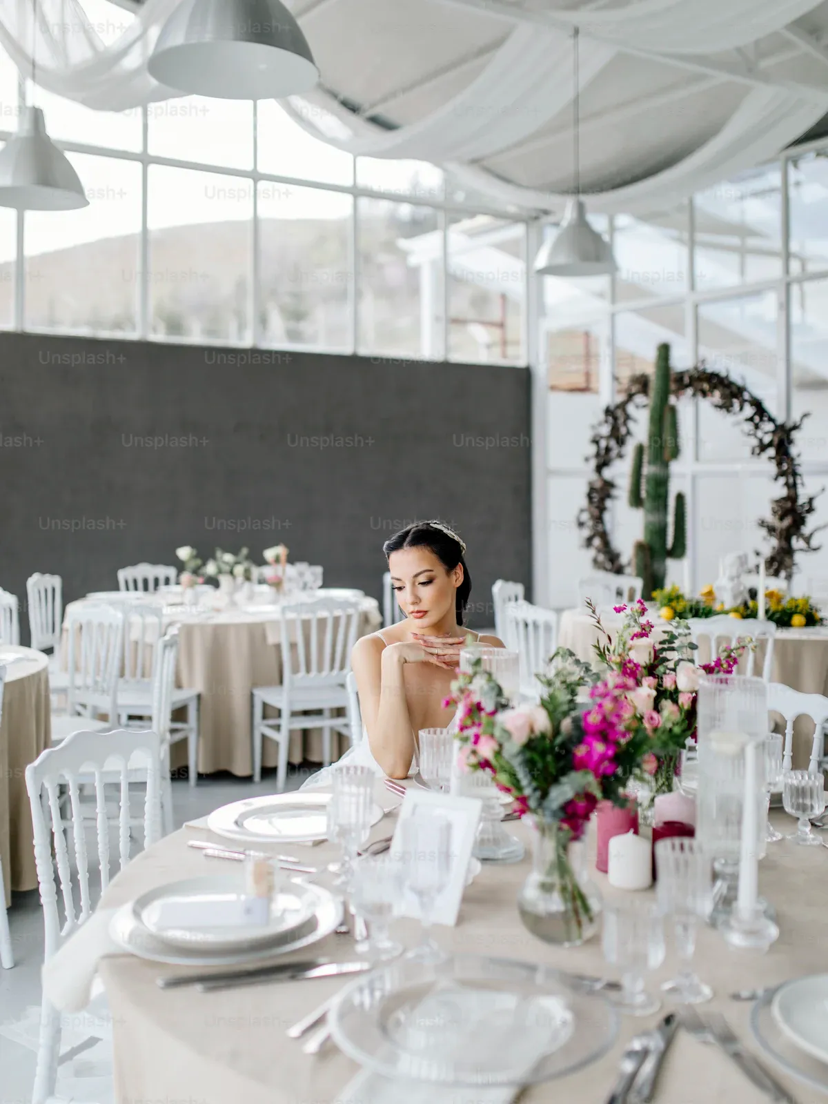 Bride seated at a dressed table in a bright glass reception hall
