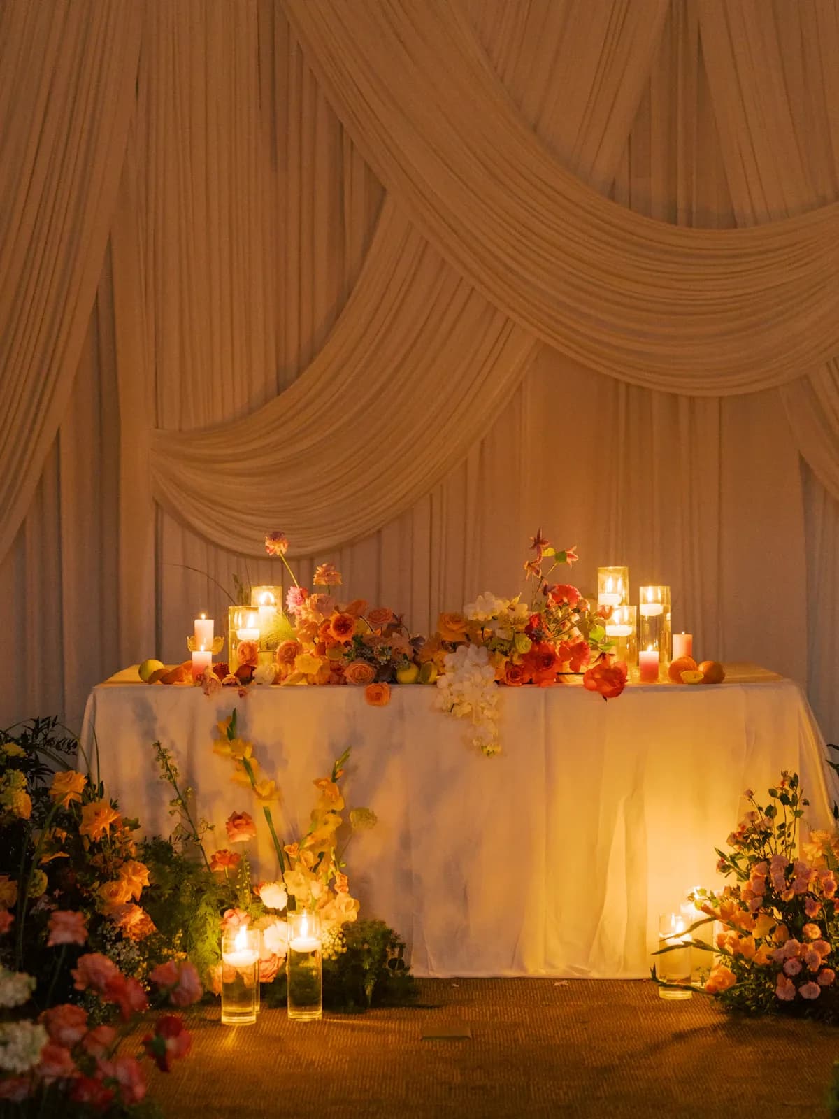 Draped backdrop with a candlelit table and flowers