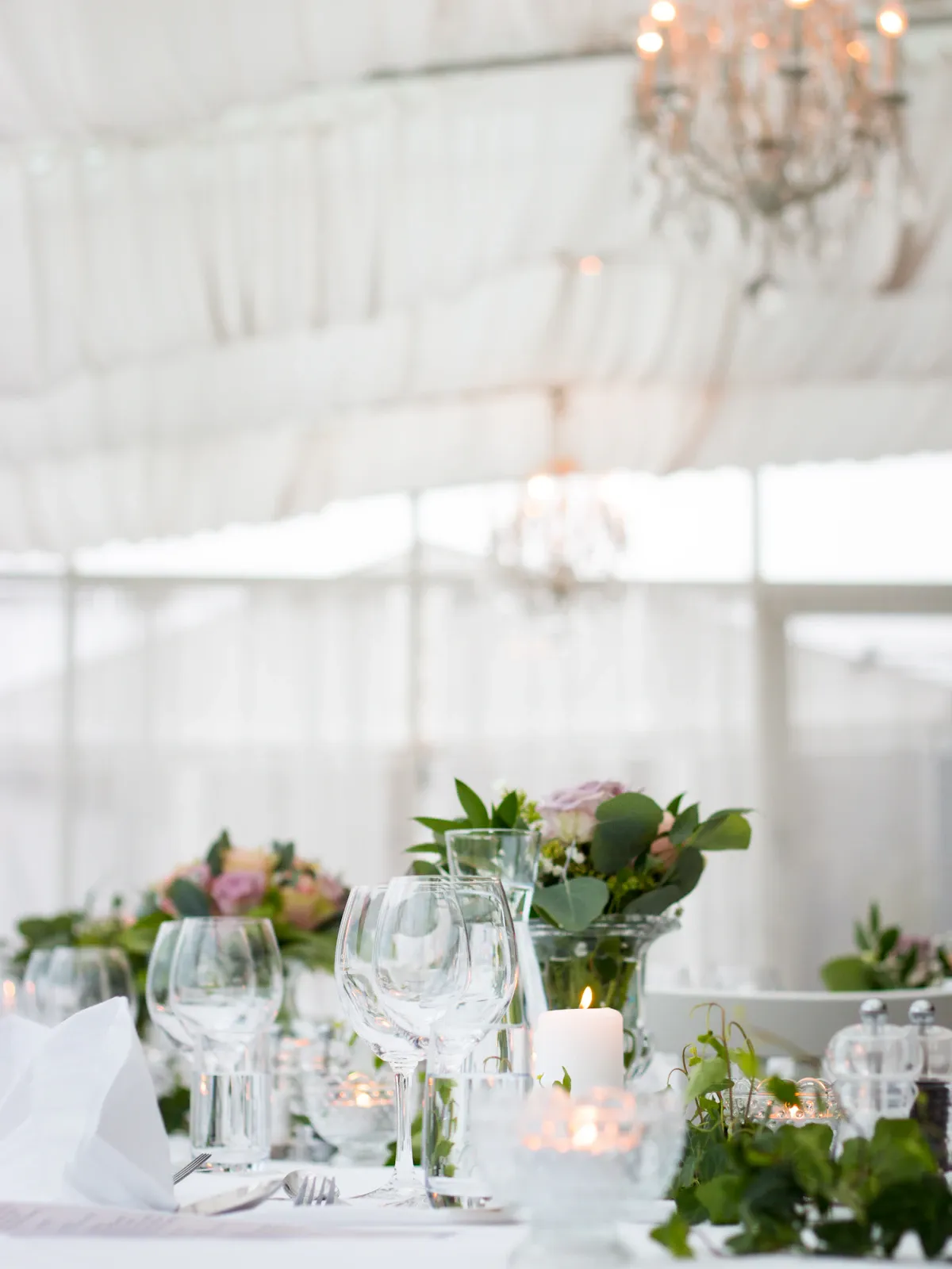 White tent reception set with dressed tables and fresh greenery
