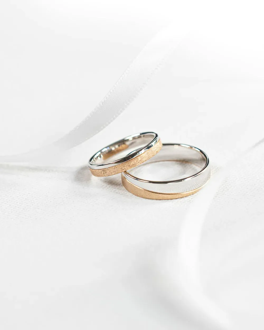 Two gold wedding rings resting on white fabric