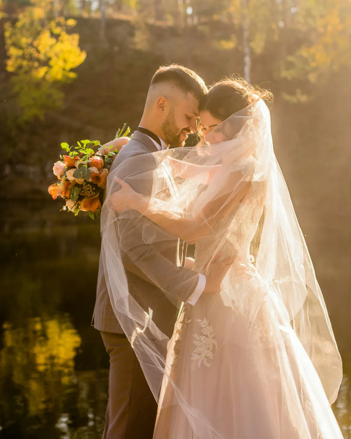 Bride and groom wrapped in a veil in golden evening light
