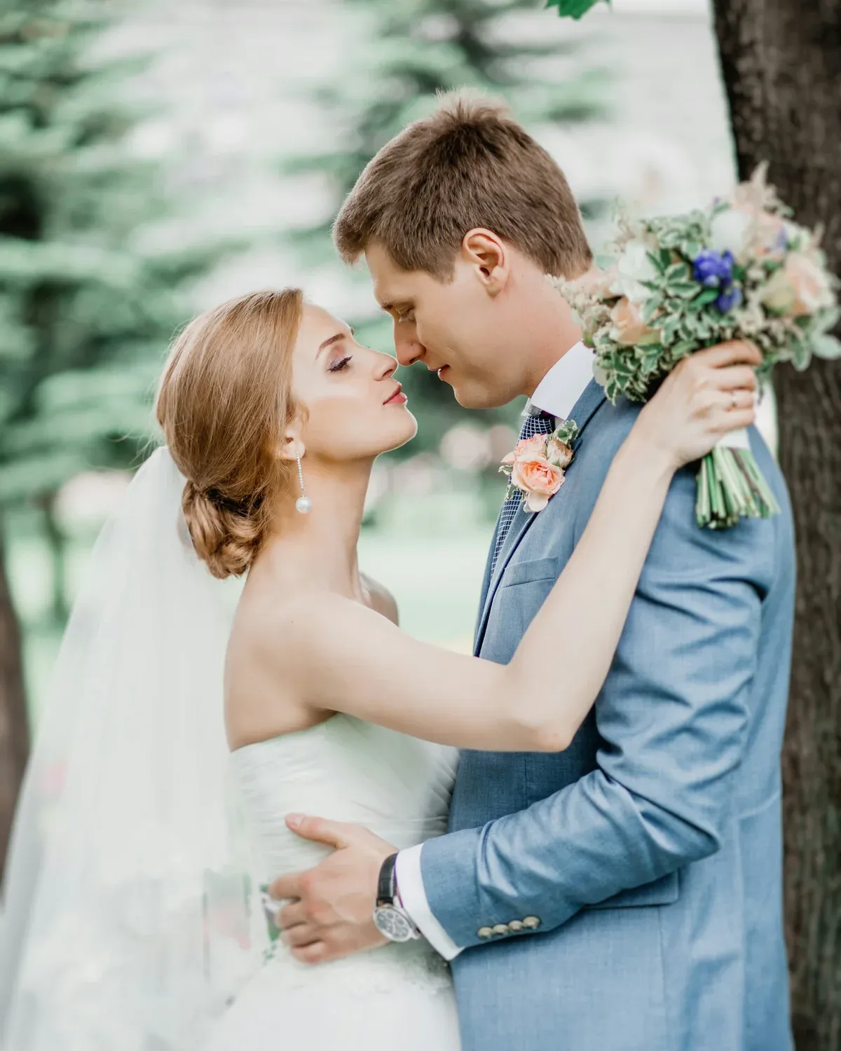 Couple embracing as the bride holds a pastel bouquet